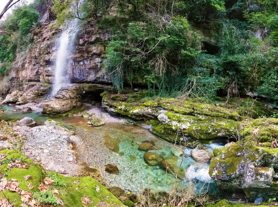 A waterfall in the mountains along a hiking path in Greece.