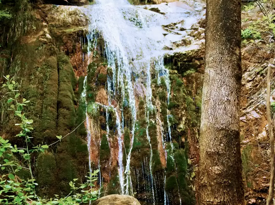 A waterfall in the mountains along a hiking path in Greece.