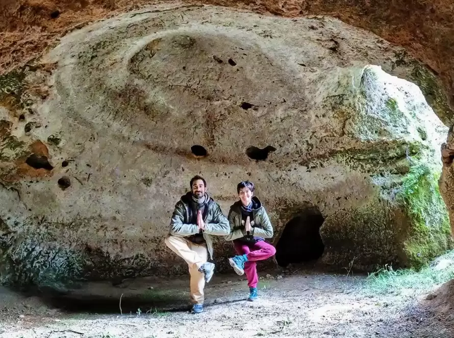Two people practicing yoga inside a cave in Greece.