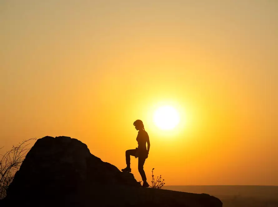 A woman hikes up a mountain during a sunset in Greece.
