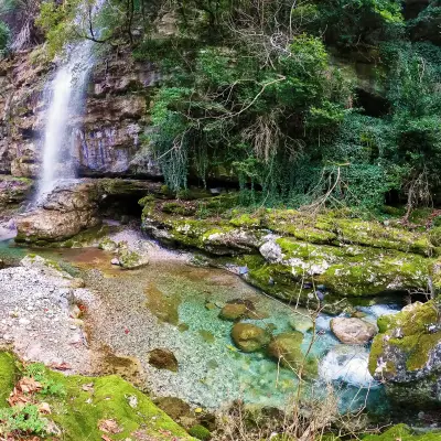 A waterfall in the mountains along a hiking path in Greece.