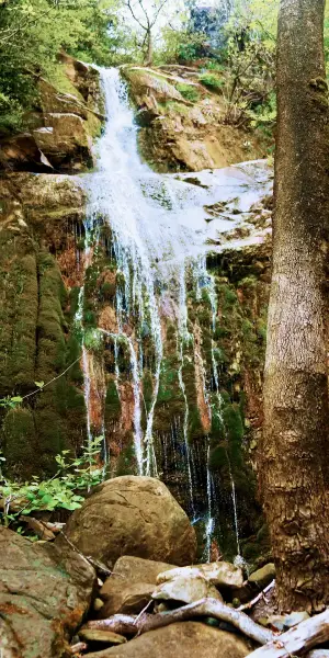 A waterfall in the mountains along a hiking path in Greece.