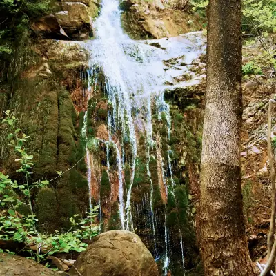 A waterfall in the mountains along a hiking path in Greece.